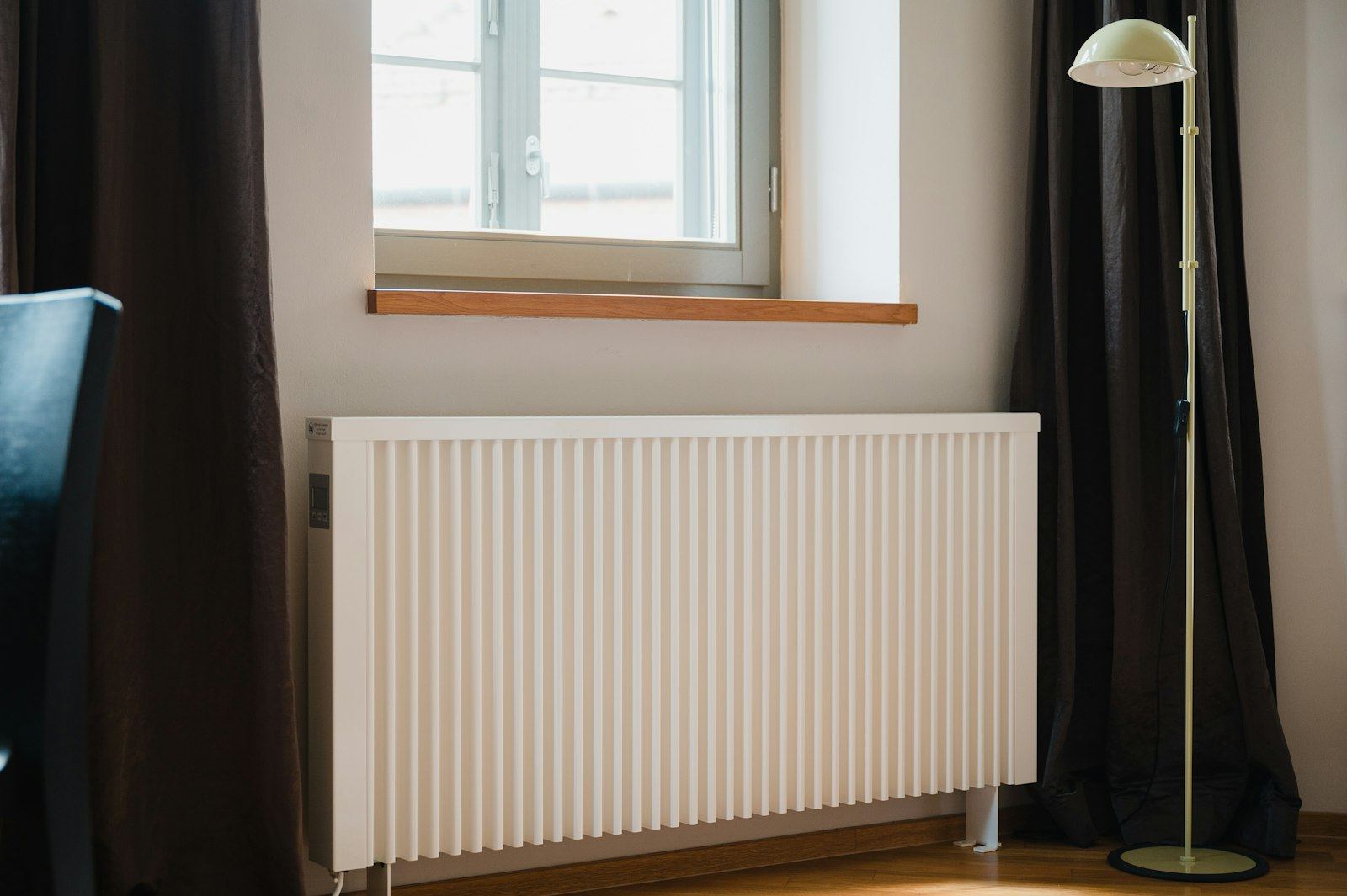 A white panel radiator under a window in a bright room